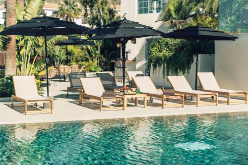 洛斯克里斯蒂亚诺斯Hotel Estefania Boutique Suites的一组椅子和遮阳伞,位于游泳池旁