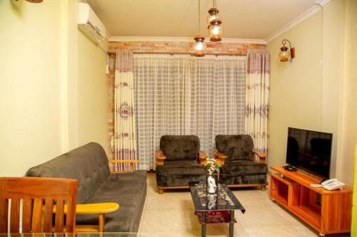 恩德培Hidden Treasure Serviced Hotel Apartments HITSHA HOTELS Entebbe的客厅配有沙发、椅子和电视