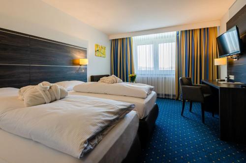 罗伊特林根Hotel Fortuna Reutlingen-Tübingen的酒店客房配有两张床和一张书桌