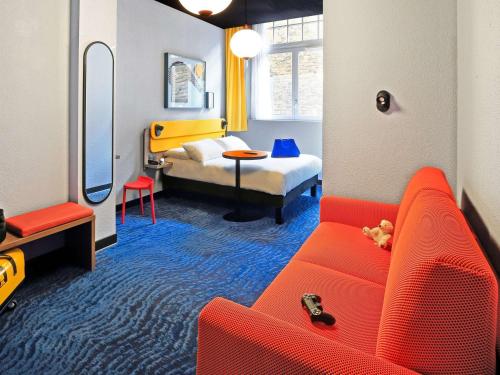 圣马洛宜必思时尚历史圣马洛中心酒店的客厅配有红色的沙发和床。