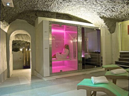 蒂拉诺Hotel Centrale Best Western Signature Collection的坐在一个粉红色灯光房间里浴缸里的女人