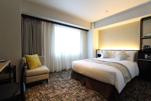 名古屋Best Western Plus Nagoya Sakae的酒店客房设有床和窗户。