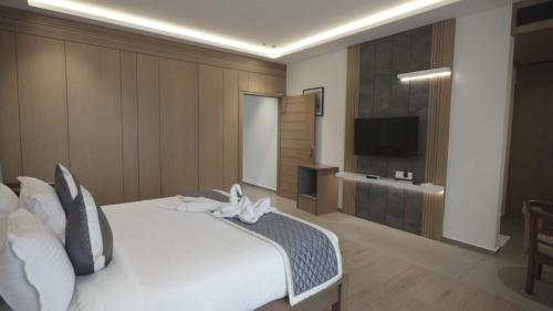 MaheRITZ AVENUE LUXURY HOTEL的卧室配有白色的床和平面电视。