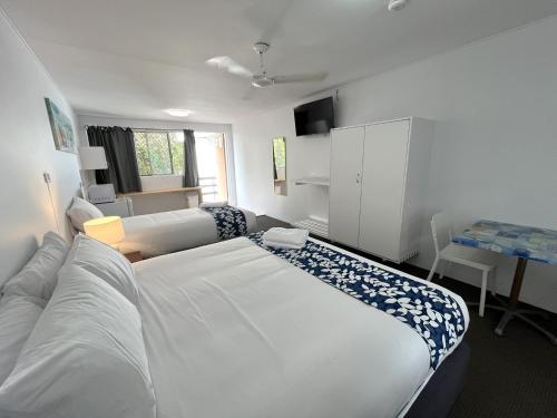 黄金海岸Browns Broadbeach的卧室配有一张白色大床和一张书桌