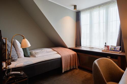哥本哈根安妮酒店的一间卧室配有一张床和一扇带灯的窗户