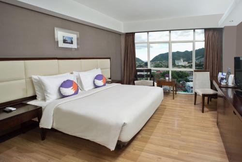 哥伦打洛省FOX Hotel Gorontalo的卧室设有一张白色大床和大窗户