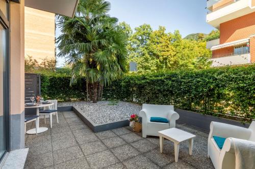 卢加诺Lake Modern Suites - Free Parking的一个带桌椅的庭院和棕榈树