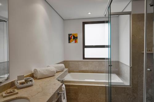 圣保罗George V Casa Branca的带浴缸和玻璃淋浴间的浴室。
