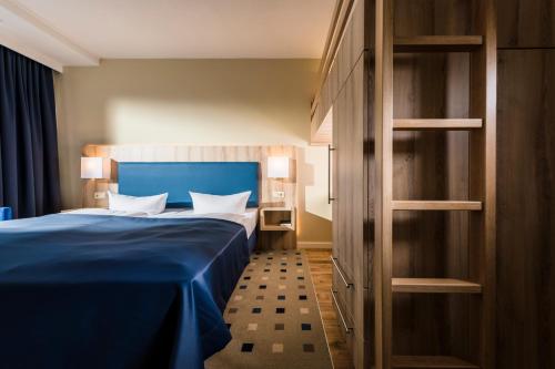 奥斯特西巴德钦诺维茨Baltic Zinnowitz - Hotel mit Meerwasserpool und Thermalbad的一间位于客房内的蓝色床卧室