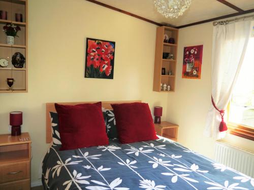 埃文河畔斯特拉特福河湾山林小屋的一间卧室配有红色枕头的床