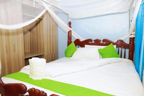 KakamegaGerly Homes的卧室配有带绿色和白色枕头的天蓬床