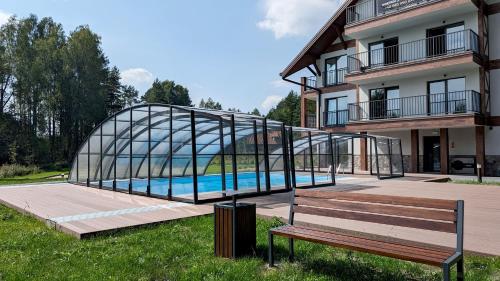 KarwicaApartamenty Sun & Snow Zapach Lasu - Naturalne SPA的一座玻璃桥,在游泳池旁的一座建筑物上