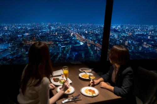 大阪ART 大阪湾酒店的一群坐在餐桌上的人,拿着盘子的食物