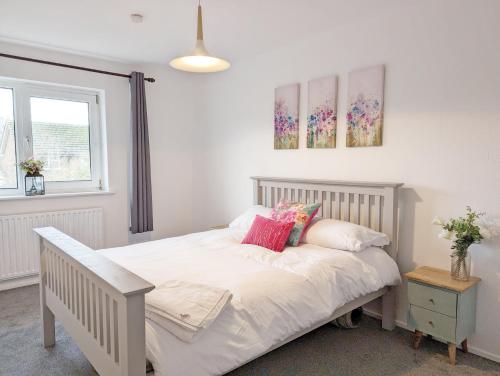 拉斯廷顿Family Home in Rustington, West Sussex的一间卧室配有带白色床单和粉红色枕头的床。