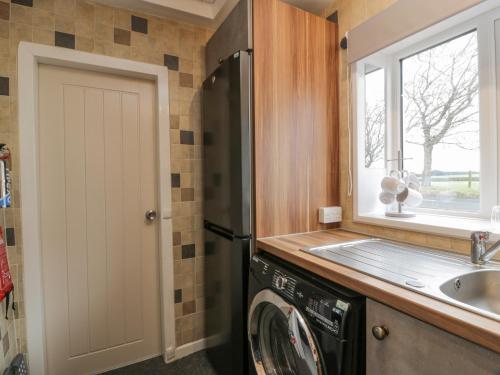 欧文Rosalin Cottage的厨房配有洗衣机和水槽