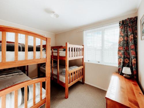 图朗伊Alpine House Tongariro - Turangi Holiday Home的一间卧室设有两张双层床和一扇窗户。