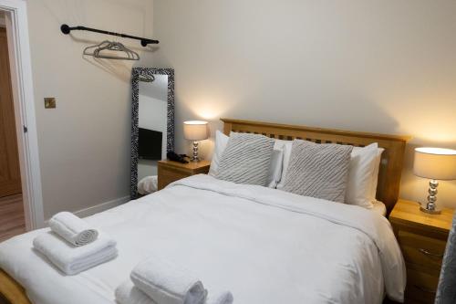 赫里福德Contemporary new build with parking & garden in central location的卧室配有一张带两盏灯和镜子的白色床。
