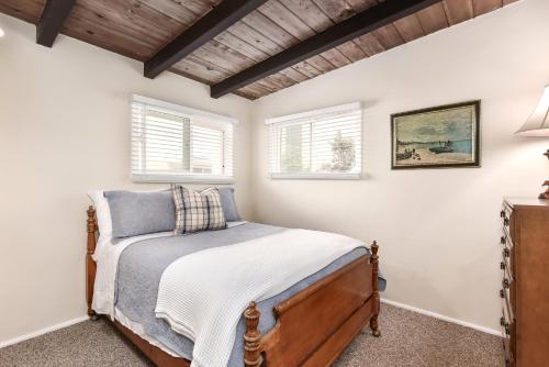 纽波特海滩West Newport Duplex on the Sand with Patio-Sleeps 12的一间卧室设有一张床和两个窗户。