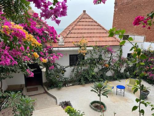 PoponguineLe Cabaoui的一座带粉红色花卉和蓝色椅子的房子