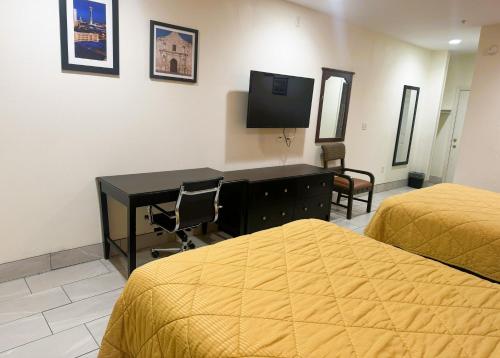圣安东尼奥Pecan Valley Inn & Suites的一间卧室配有两张床、一张桌子和一台电视。