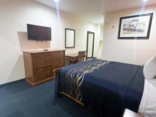 圣安东尼奥Pecan Valley Inn & Suites的酒店客房配有一张床、一张书桌和一台电视。