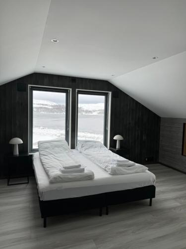希尔科内斯Arctic Sea Breeze的一张大床,位于带两个窗户的房间