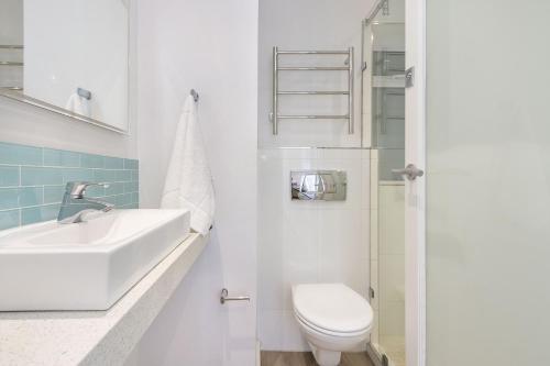 布鲁堡史特兰Portico 704的白色的浴室设有水槽和卫生间。