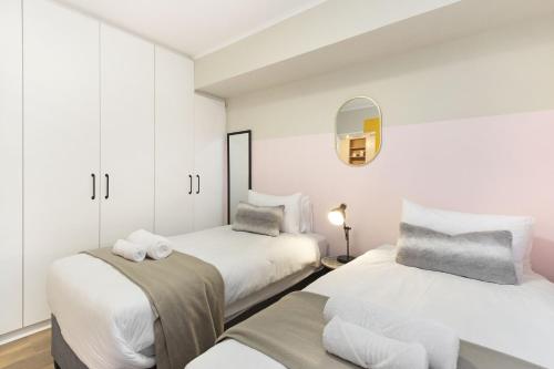开普敦Mayfair Luxury 212的配有2张床的白色墙壁和镜子