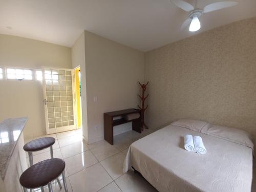 西波山Chalé Cipó Maia的一间卧室配有一张床、一张桌子和两张凳子