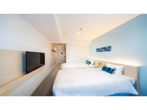 宫古岛Hotel Torifito Miyakojima Resort - Vacation STAY 79481v的酒店客房设有两张床和一台平面电视。