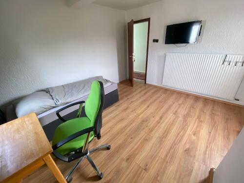 BrombachtalEinfache Schlafmöglichkeit mit Gemeinschaftsküche und Bad的客房设有绿色椅子、一张床和一张书桌