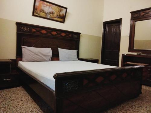 卡拉奇Four Season 1 Airport Guest House的一间卧室配有一张大床和木制床头板