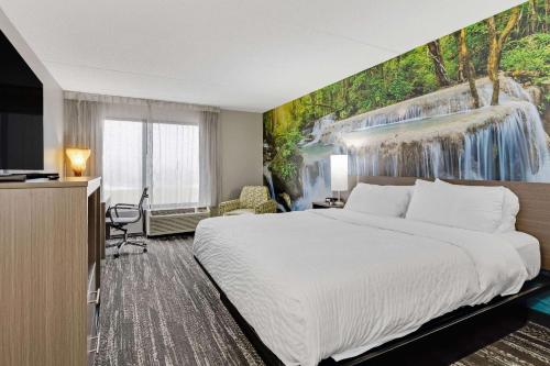 伊利Clarion Pointe by Choice Hotel的酒店客房,设有床铺和瀑布壁画