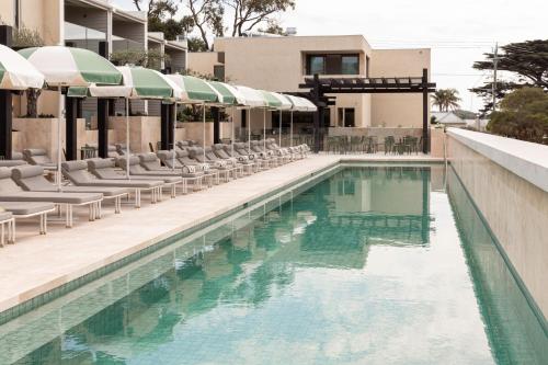 索伦托索伦托酒店的一个带椅子和遮阳伞的游泳池