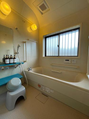 宫崎貸切宿KUMANO的带浴缸、卫生间和窗户的浴室