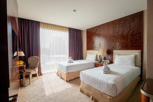 万隆Belviu Hotel Bandung的酒店客房设有两张床和窗户。