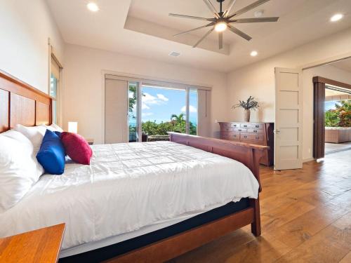 科纳Kukui Hale at Makalei Estates的一间卧室配有一张大床和吊扇