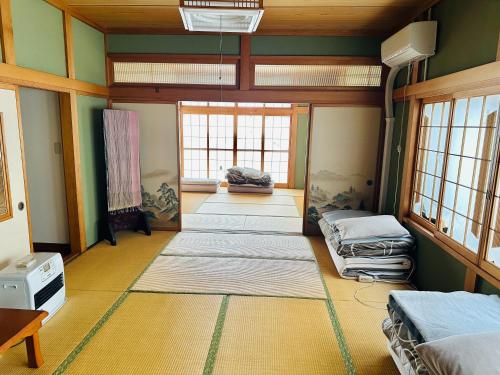 八户市青森伝統芸能を楽しめる繭子の宿的带窗户的客房内配有几张床垫的房间