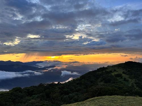 马迪凯里Coorg Cu’s Homestay的云雾 ⁇ 的山顶上的日落