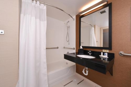 奥兰多奥兰多机场费尔菲尔德客栈的一间带水槽、浴缸和镜子的浴室
