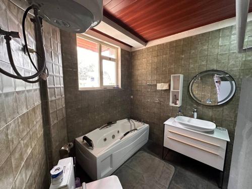 亚的斯亚贝巴Kebena spacious room with private jacuzzi and walk in closet的带浴缸、水槽和镜子的浴室
