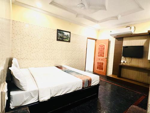 维杰亚瓦达HOTEL TEJASRI RESIDENCY的配有一张床和一台平面电视的酒店客房