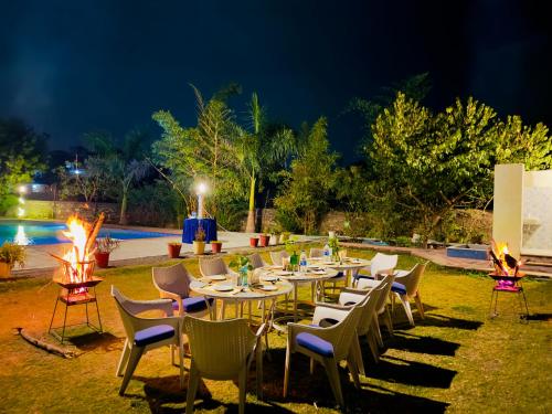 乌代浦Jag Aravali Resort Udaipur- Experience Nature away from city Hustle的一群桌子和椅子在晚上在院子里
