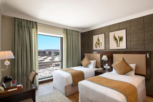 麦地那The Oberoi Madina المدينة أوبروي的酒店客房设有两张床和窗户。