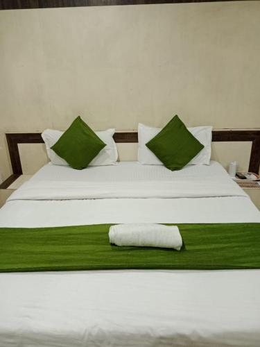 贾巴尔普尔Hotel Cozy Residency的一张带绿色枕头的白色床和毛巾