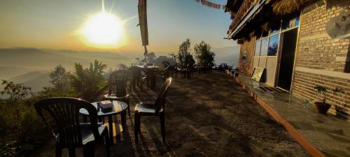 PanaotiDadaghare Homestay & View Point Restaurant的露台上的一组桌椅,享有日落美景