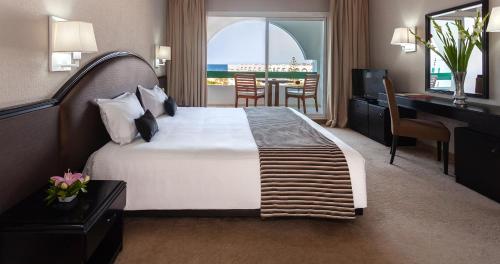 甘达坞伊港El Mouradi Palace的酒店客房设有一张大床和一张书桌。
