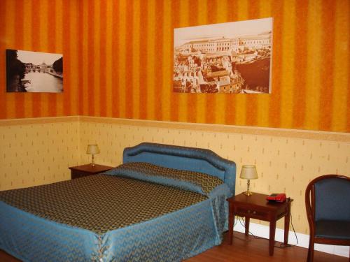 科森扎Hotel Excelsior的一间卧室配有蓝色的床,配有两张桌子和两张图片