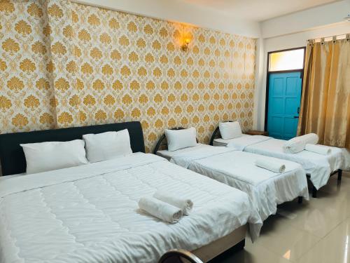 勿洞SB Betong ห้องพักรายวัน的一间卧室配有两张带白色床单和墙壁的床。
