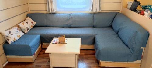 加斯泰MOBIL HOME 43 dans Camping 4 Etoiles的一张蓝色的沙发,位于一个小房间里,配有桌子